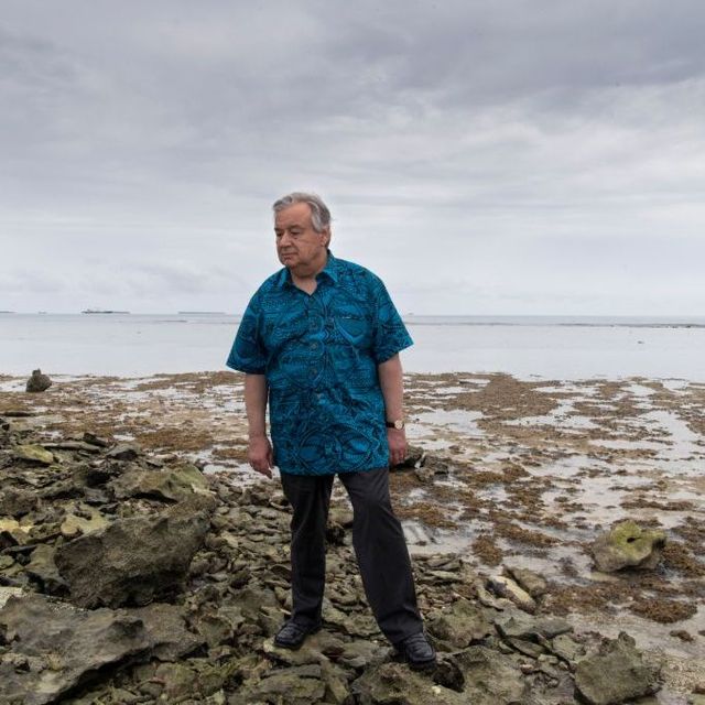 Generalsekretär António Guterres steht am Strand von Tuvalu, an dem sehr viel Treibgut angespült wurde. Er sieht besorgt aus.