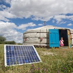 Im Vordergrund sieht man ein Solarpanel auf einer grünen Wiese, im Hintergrund ist eine mongolische Jurte zu sehen.