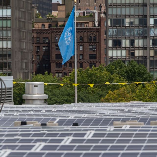 Auf dem Dach sind Solarmodule installiert, im Hintergrund weht die blaue UN-Flagge.