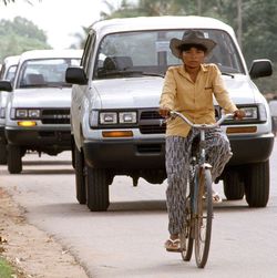 Eine Fahrradfahrerin fährt vor einer langen Reihe an weißen Autos.