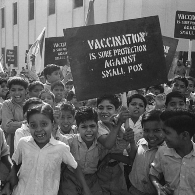 Kinder tragen Schilder, die die Menschen aufforderten, sich impfen zu lassen.