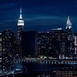Skyline von New York mit vielen erleuchteteten Gebäuden, in der Mitte das dunkle UN-Gebäude.