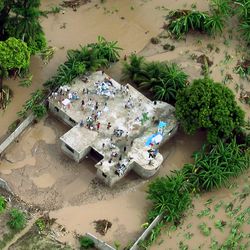 Eine Luftansicht eines Hausdaches, auf das sich Menschen gerettet haben, umgeben von einer Überschwemmung
