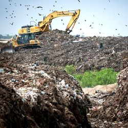 Ein Bagger gräbt in einer Müllhalde in Bangladesch.