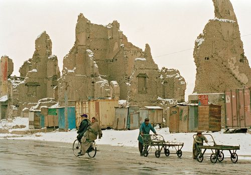 Einwohner Kabuls inmitten der durch den Bürgerkrieg in Afghanistan verursachten Zerstörungen, 2002. Einige afghanische Menschen vor den Ruinen zerstörter Häuser.