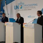 Drei Männer stehen an drei Redepulten vor einem Banner