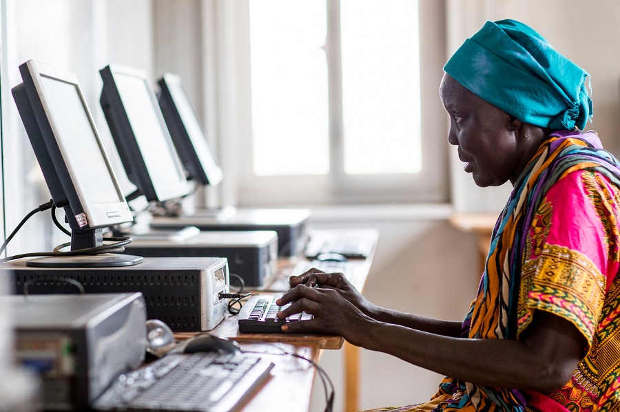 Eine ältere afrikanische Frau sitzt vor einem Computer.